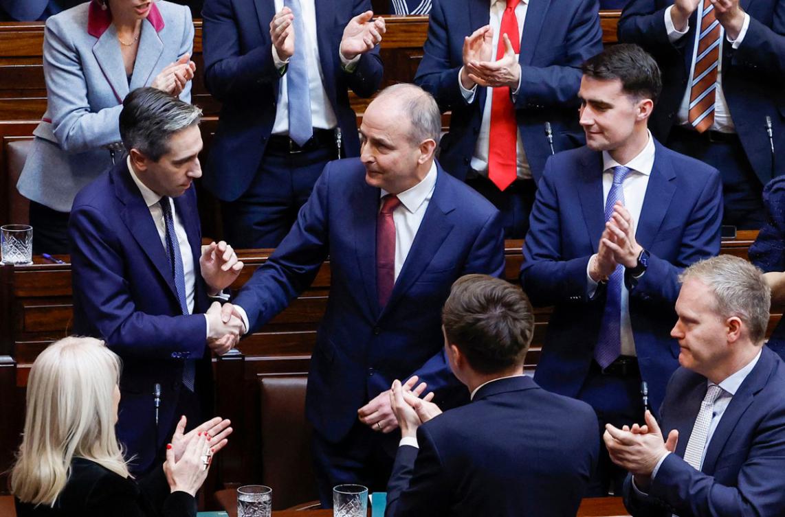 Ireland's Prime Minster, Micheal Martin, being congratulated by outgoing Prime Minister and Fine Gael leader and Simon Harris (L) in the Dail, the lower house of the Irish parliament, in Dublin. (File/AFP)