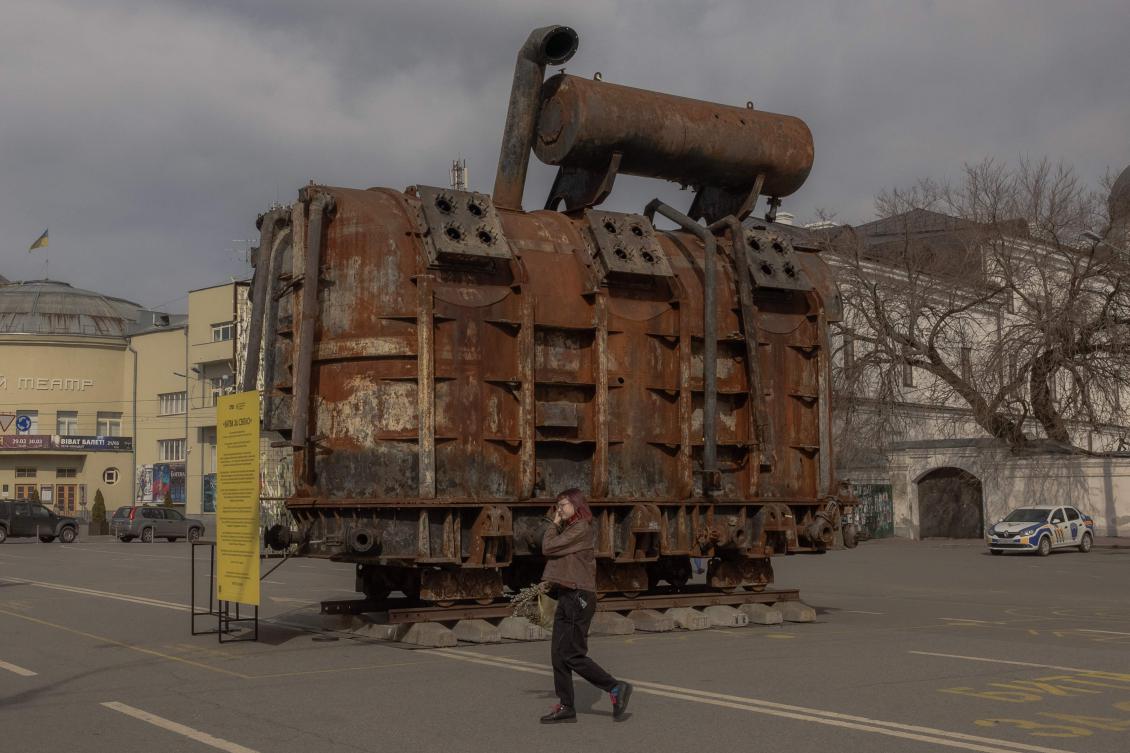 A woman walks past heavily damaged by Russian attack Ukrainian thermal power plant equipment placed on display in Kyiv, March 10, 2025. (AFP)