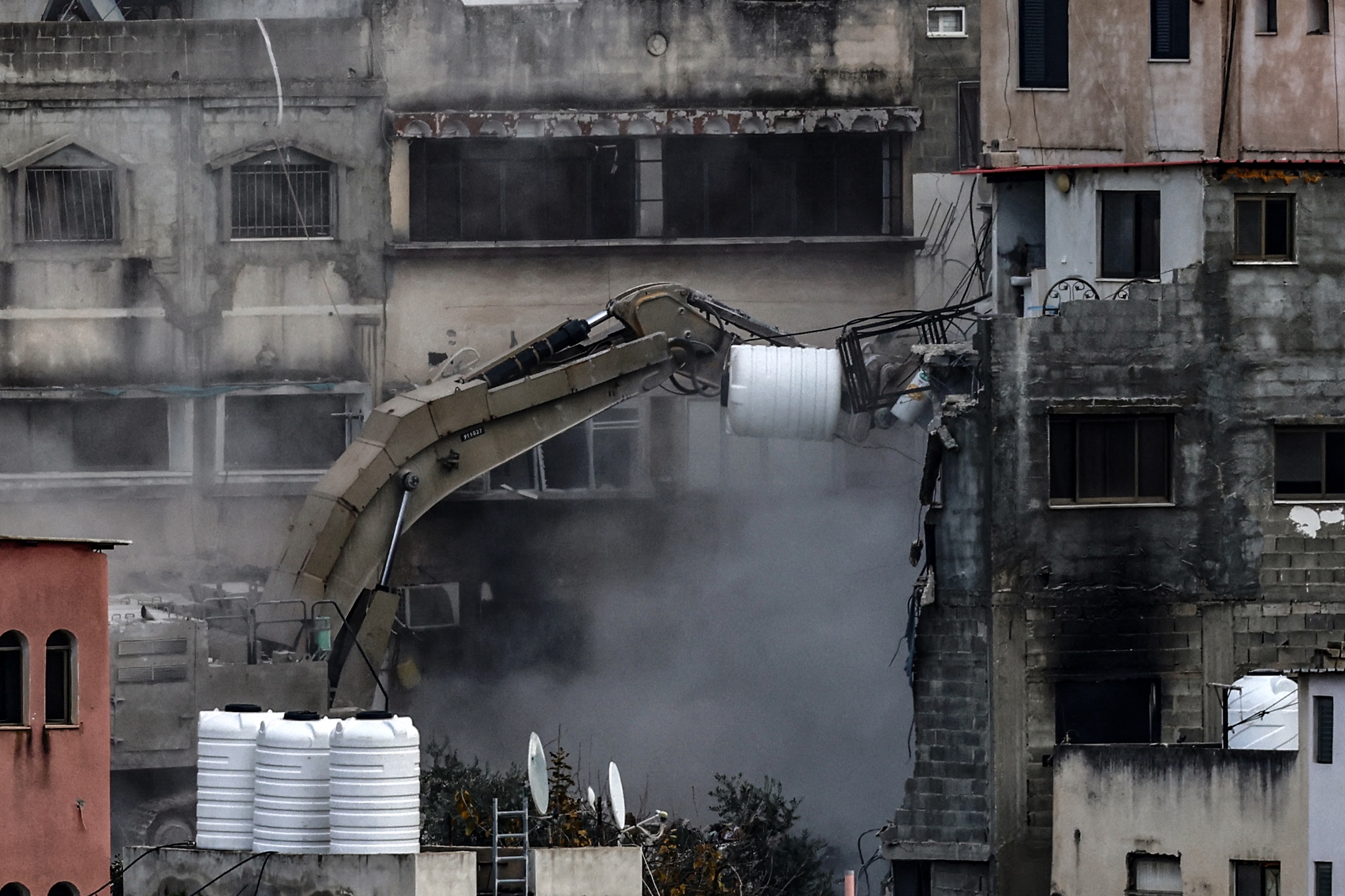 An Israeli military excavator demolishes a building in the Nur Shams camp for Palestinian refugees east of Tulkarem, amid an ongoing offensive in the occupied-West Bank, March 6, 2025. (AFP)