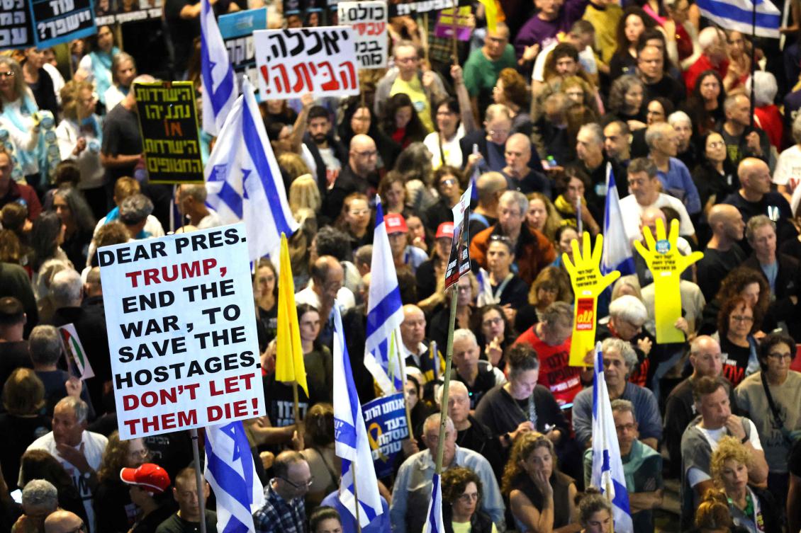 Demonstrators raise placards and wave Israeli flags during a protest calling for action to release the remaining hostages held captive in Gaza since the 2023 Oct. 7 attacks by Palestinian militants, outside the Israeli Defense Ministry headquarters in Tel Aviv on Mar. 15, 2025. (AFP)