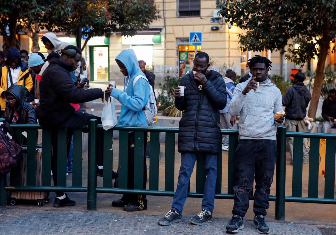 Immigrant people eat an iftar meal during the food distribution organized by a group of Senegalese people during Ramadan in Lavapies Square in Madrid, on March 19, 2025. (AFP)