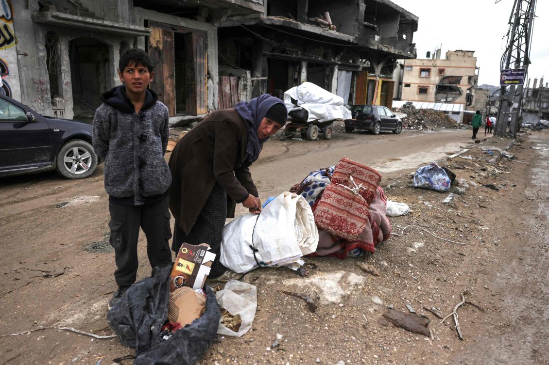 A Palestinian youth looks on as a woman prepares her belongings to flee Beit Lahia in the Northern Gaza Strip on Mar. 21, 2025. (AFP)