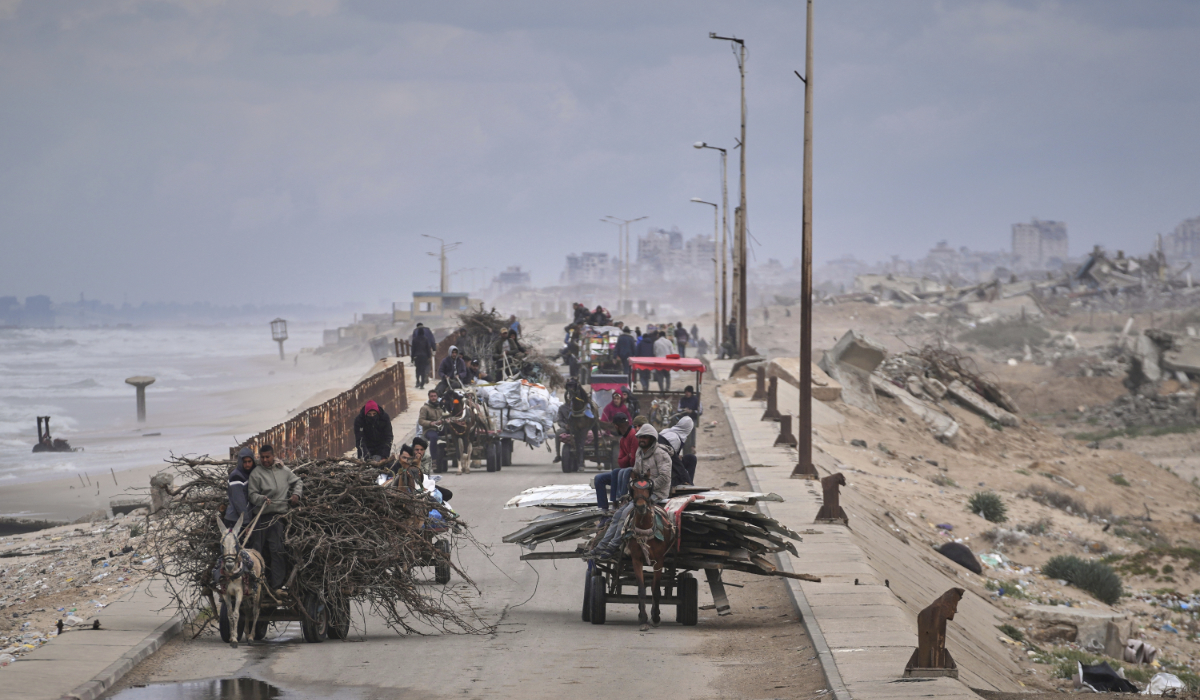 Displaced Palestinians, carrying their belongings, wood and other items, move between southern and northern Gaza along a beach road away from the areas where the Israeli army is operating after Israel's renewed offensive in the Gaza Strip, in the outskirts of Gaza City, Friday March 21, 2025. (AP)