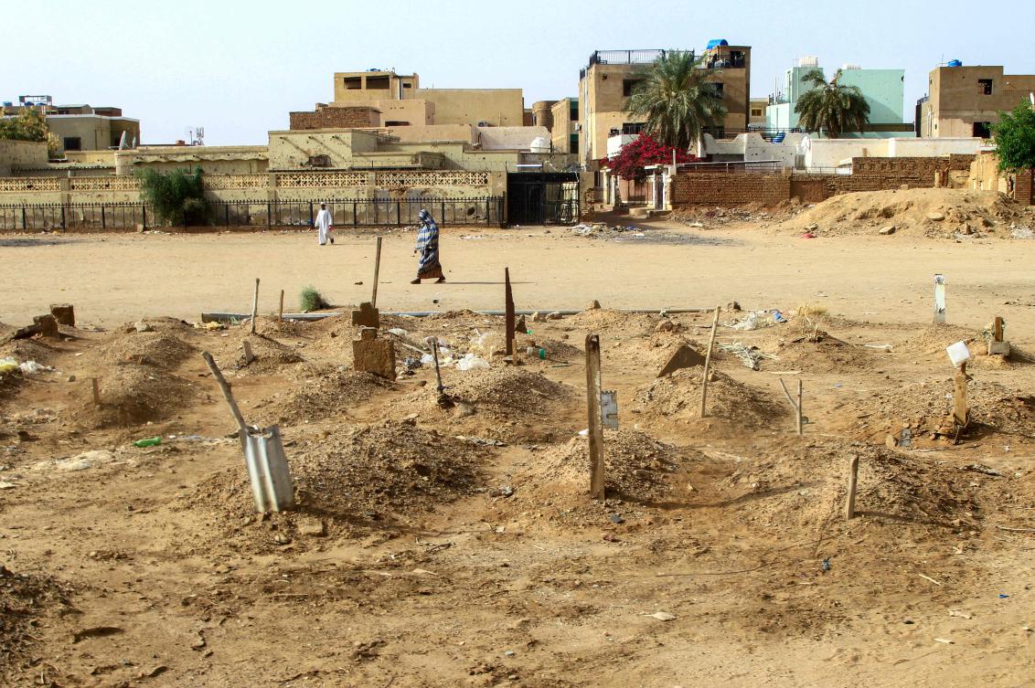 A Sudanese woman walks past graves of people killed during clashes lining the streets of Khartoum's twin-city Omdurman on March 20, 2025. (AFP)