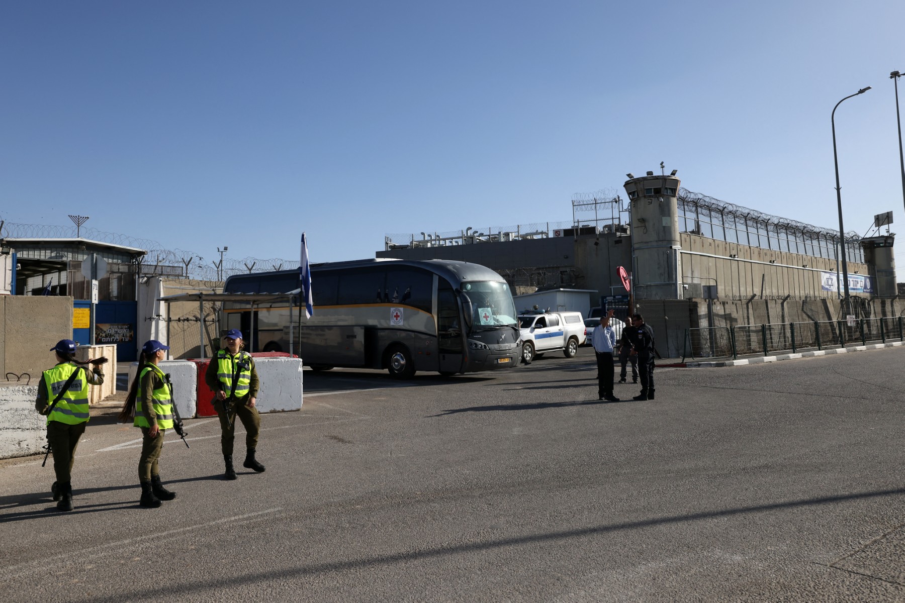 Members of the Israeli security forces stand guard as a bus belonging to the International Red Cross is parked outside of the Ofer military camp near the occupied West Bank city of Ramallah (AFP)