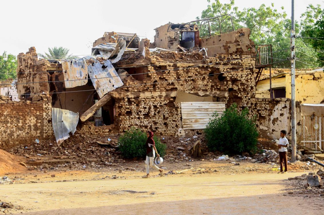 A Sudanese boy looks on as a woman walks past a damaged building in Khartoum's twin-city Omdurman on March 20, 2025. (AFP)