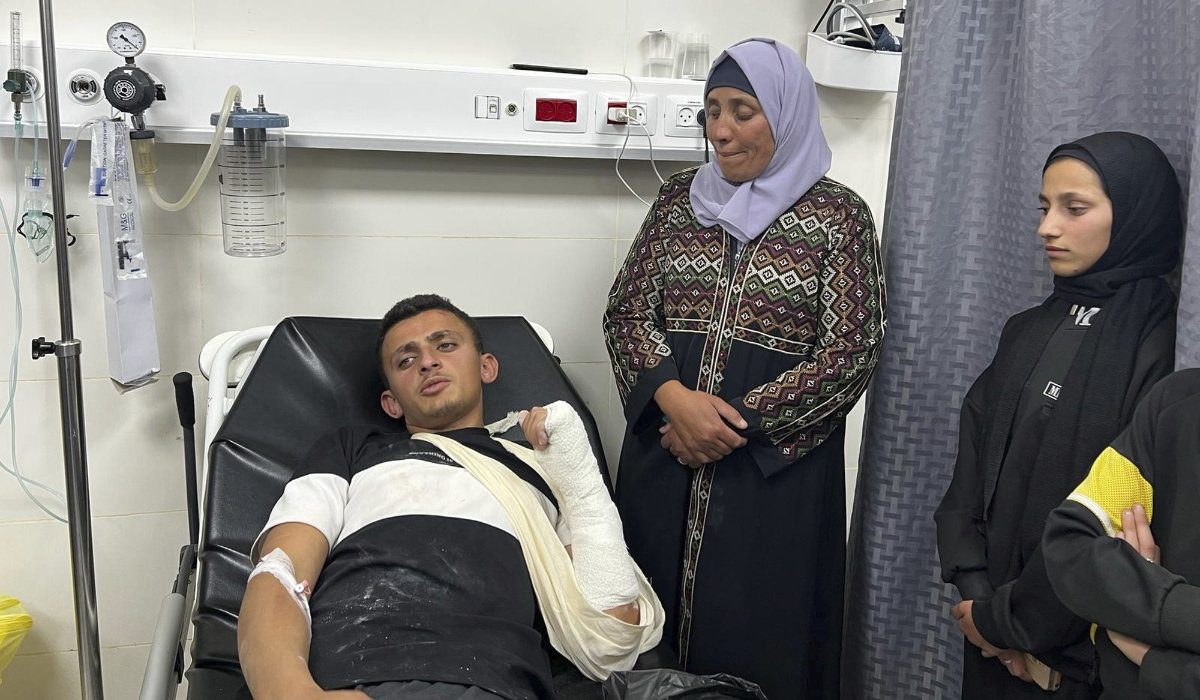 Palestinian Qusai Al-Amur sits in a hospital bed next to his relatives following an attack by Israeli settlers on his West Bank village of Jinba, Friday, March 28, 2025. (AP)
