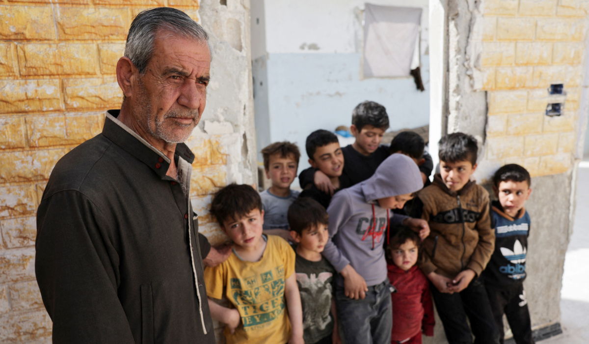 Hassan al-Ahmad, 65, stands with his children and grandchildren inside his damaged house, as returning Syrians prepare to celebrate Eid al-Fitr, in Idlib, Syria March 28, 2025. (REUTERS)