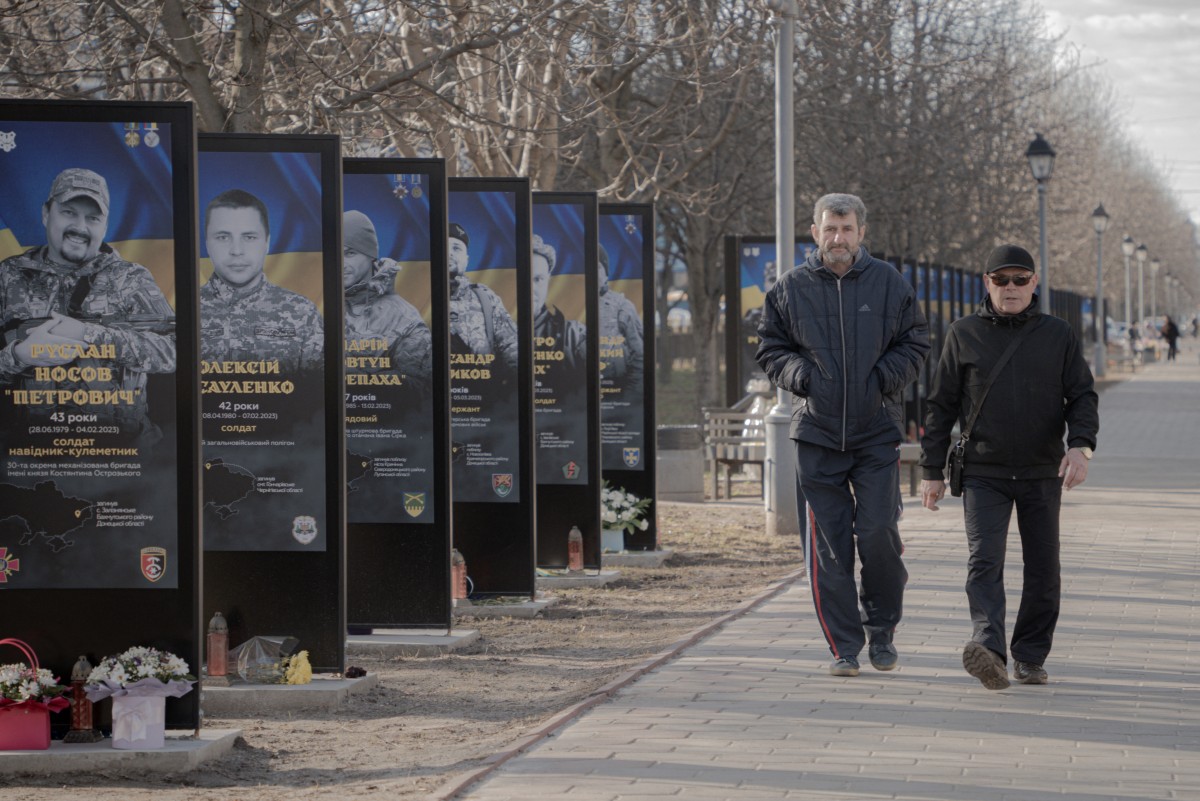 Men walk next to billboards depicting portraits of fallen Ukrainian soldiers (AFP)