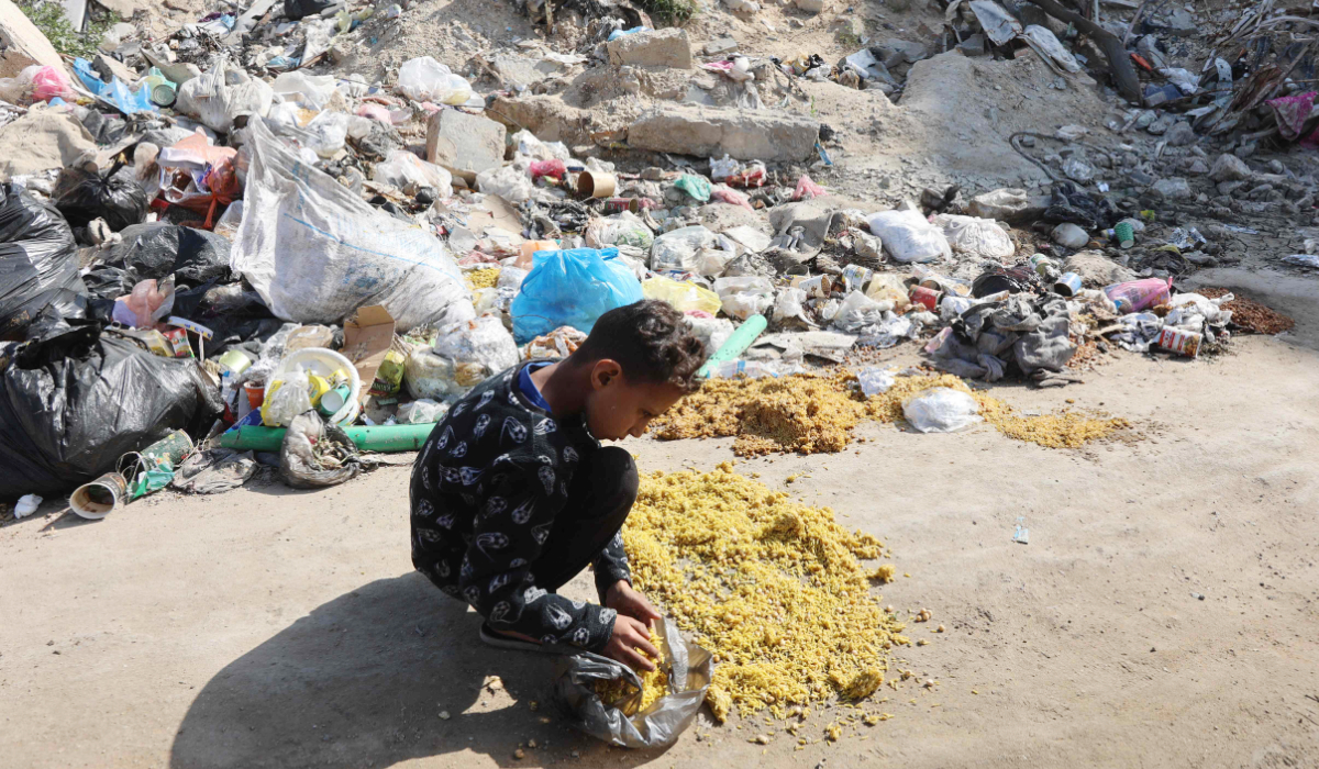 A Palestinian child collects food dropped on a street in Gaza City on March 30, 2025, during Eid al-Fitr which marks the end of the holy fasting month of Ramadan. (AFP)