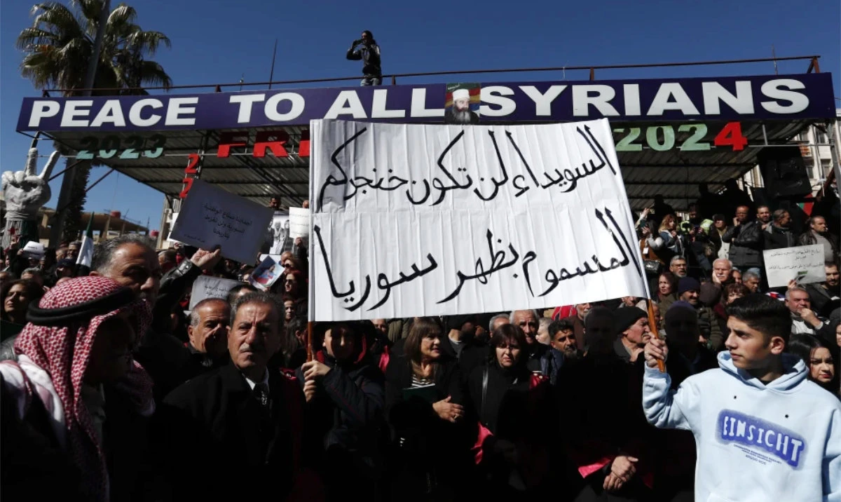 Syrian Druze hold up a placard in Arabic reads “Sweida will not be your poisoned dagger in Syria’s back.” as stage a demonstration against Israeli incursions into Syrian territory in the southern province of Sweida, Syria, Tuesday, Feb. 25, 2025. (AP)