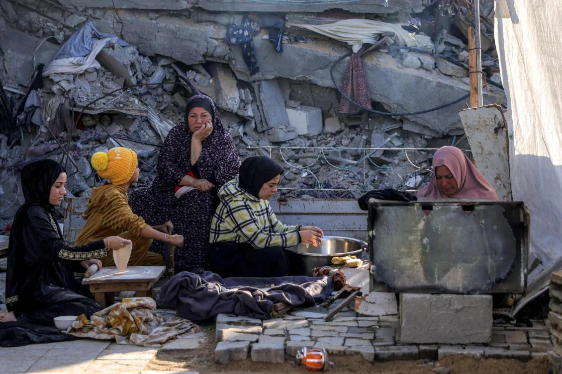Women prepare food for iftar on the first day of Ramadan, as they sit by the rubble of a collapsed building in a shelter in Jabalia in the northern Gaza Strip on March 1, 2025. (AFP)