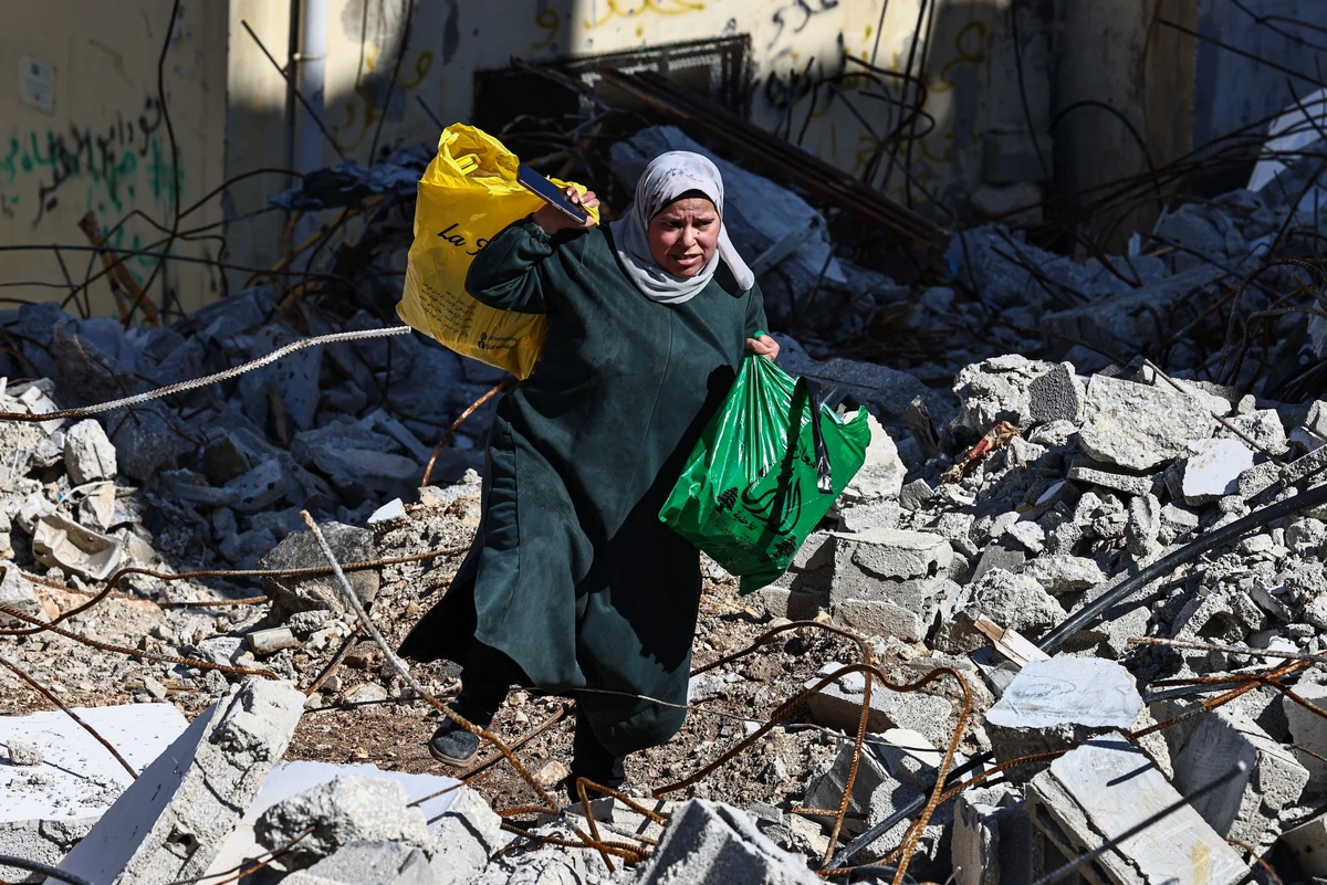 A woman carries bags as she walks on rubble at the Nur Shams camp for Palestinian refugees near Tulkarem in the occupied West Bank, Feb. 26, 2025. (AFP)