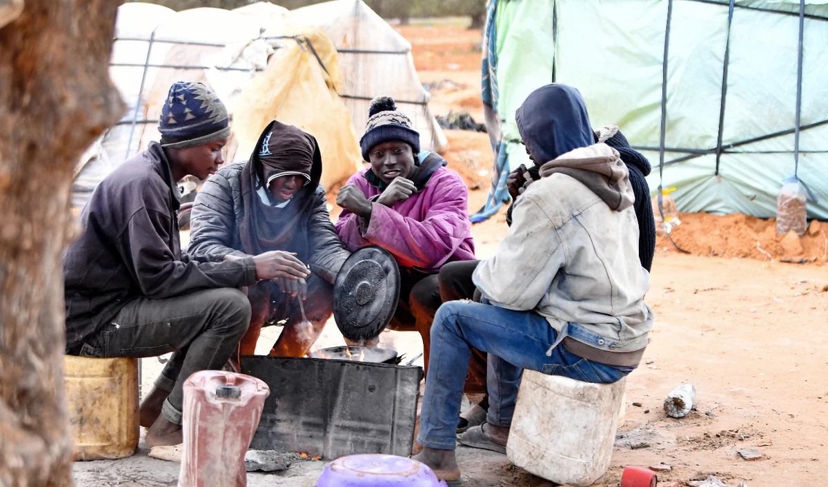 Migrants gather around a fire at a camp in Jebeniana in Tunisia’s Sfax governorate. (File/AFP)