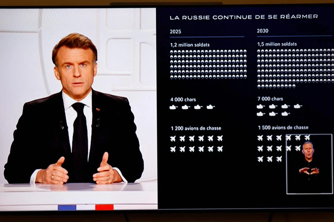 A television screen broadcasting France’s President Emmanuel Macron (L) addressing a live interview next to a graph showing the projected evolution of the Russian army, on French TV at the Elysee Presidential Palace in Paris. (AFP)
