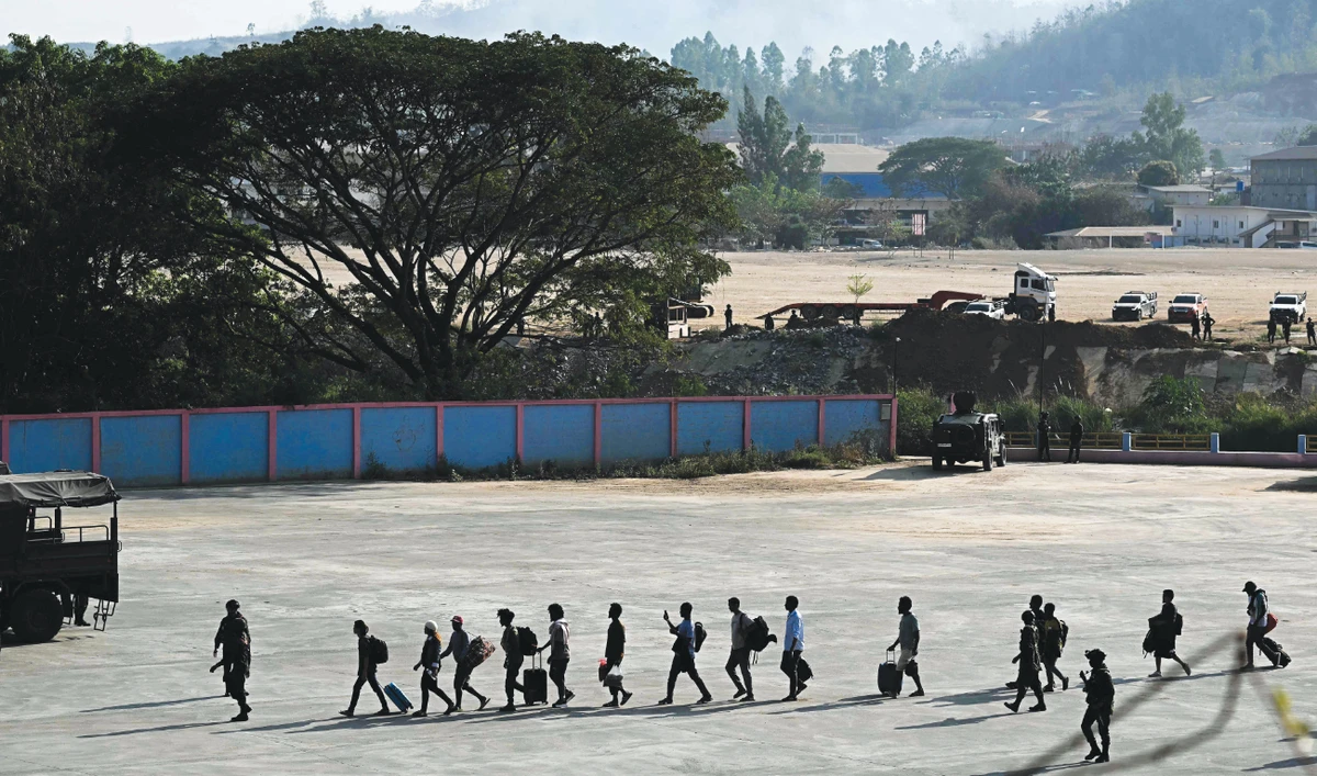 Alleged victims of scam centers in Kyauk Khet in Myanmar’s Kayin State walk in line as they are met by the Thai Army. (AFP)