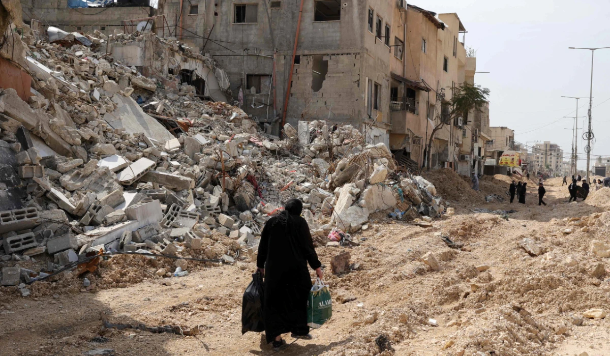 A woman carrying some personal items walks along a devastated street as she leaves the Nur Shams camp for Palestinian refugees, where Israeli forces allowed residents to retrieve belongings after issuing reported demolition notifications for several houses, in the occupied West Bank on March 5, 2025. (AFP)