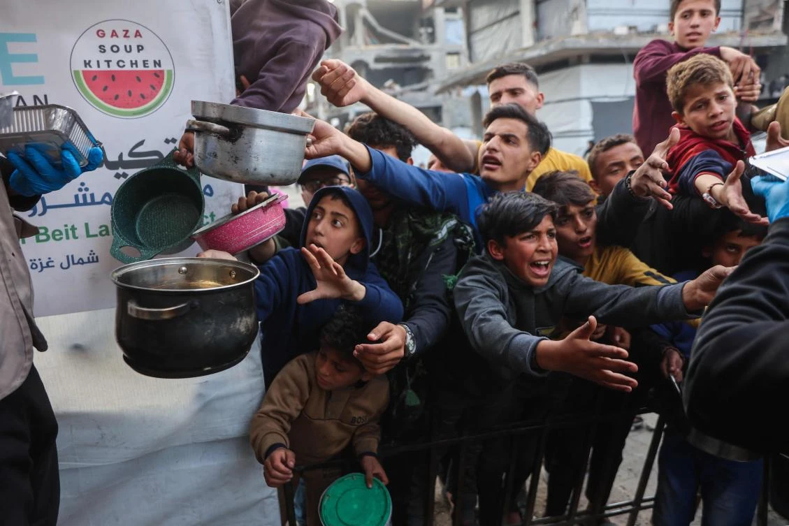 Displaced Palestinian children push into a queue to get a portion of cooked food from a charity kitchen in Beit Lahia in northern Gaza Strip, ahead of iftar during Ramadan on March 9, 2025. (AFP)