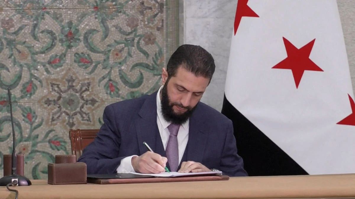 Syria's interim President Ahmed Al-Sharaa signs a constitution draft, after Syrian committee of legal experts submitted it, in Damascus, Syria, March 13, 2025, in this screengrab obtained from a video. (Reuters)