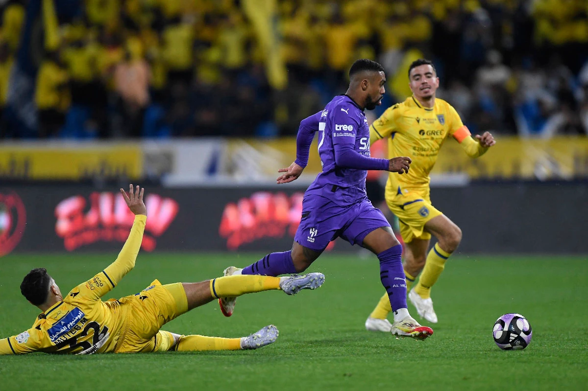 Al-Hilal's Mohamed Kanno in action with Al-Taawoun's Mohammed Mahzariat the King Abdullah Sports City Stadium in Buraidah on March 15, 2025. (REUTERS)