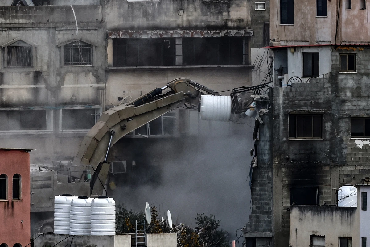 An Israeli military excavator demolishes a building in the Nur Shams camp for Palestinian refugees east of Tulkarem, amid an ongoing offensive in the occupied-West Bank, March 6, 2025. (AFP)