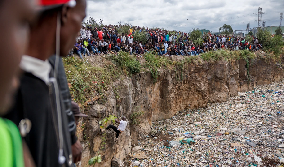 Crowds gather on the edge of an abandoned quarry to watch volunteers searching through a rubbish dump for human remains at Mukuru slum in Nairobi on July 14, 2024. (AFP)