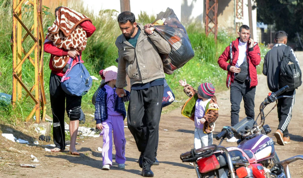 People enter northern Lebanon after crossing the Nahr Al-Kabir river with Syria's western coastal province in the Hekr Al-Daher area on March 11, 2025. (AFP)