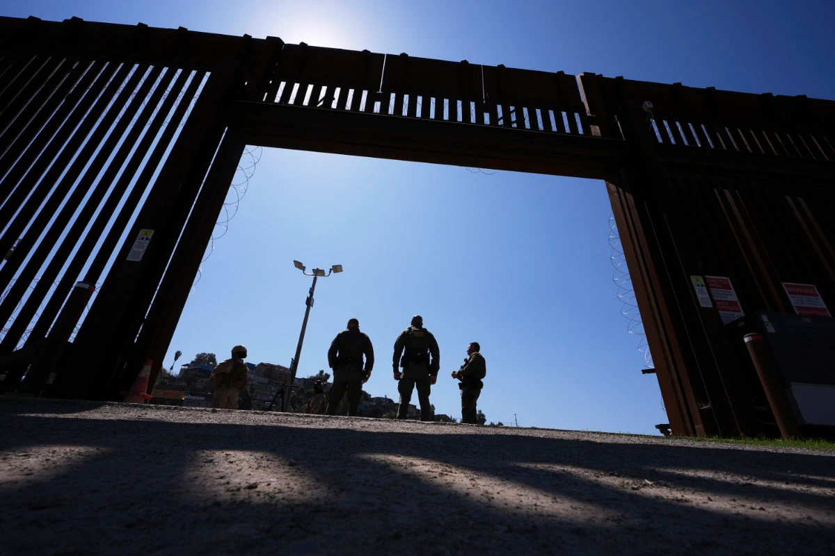 Border Patrol agents and members of the military stand inside a gate in one of two border walls separating Mexico from the US March 21, 2025, in San Diego, California. (AP Photo)