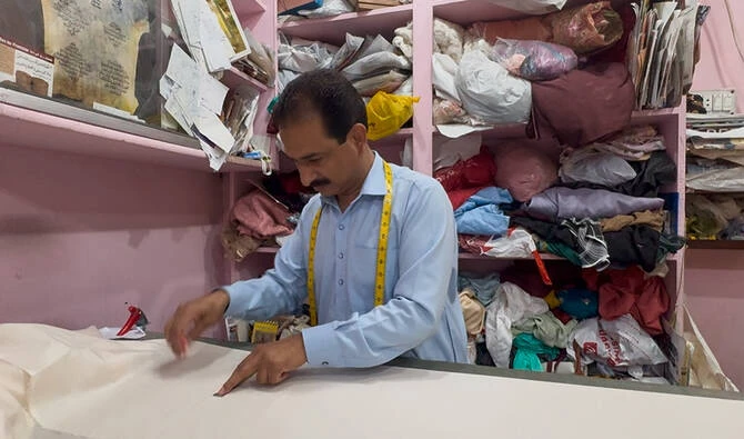 Tailor Muhammad Shafiq marks fabric before cutting it in his shop in Islamabad. (AN photo)