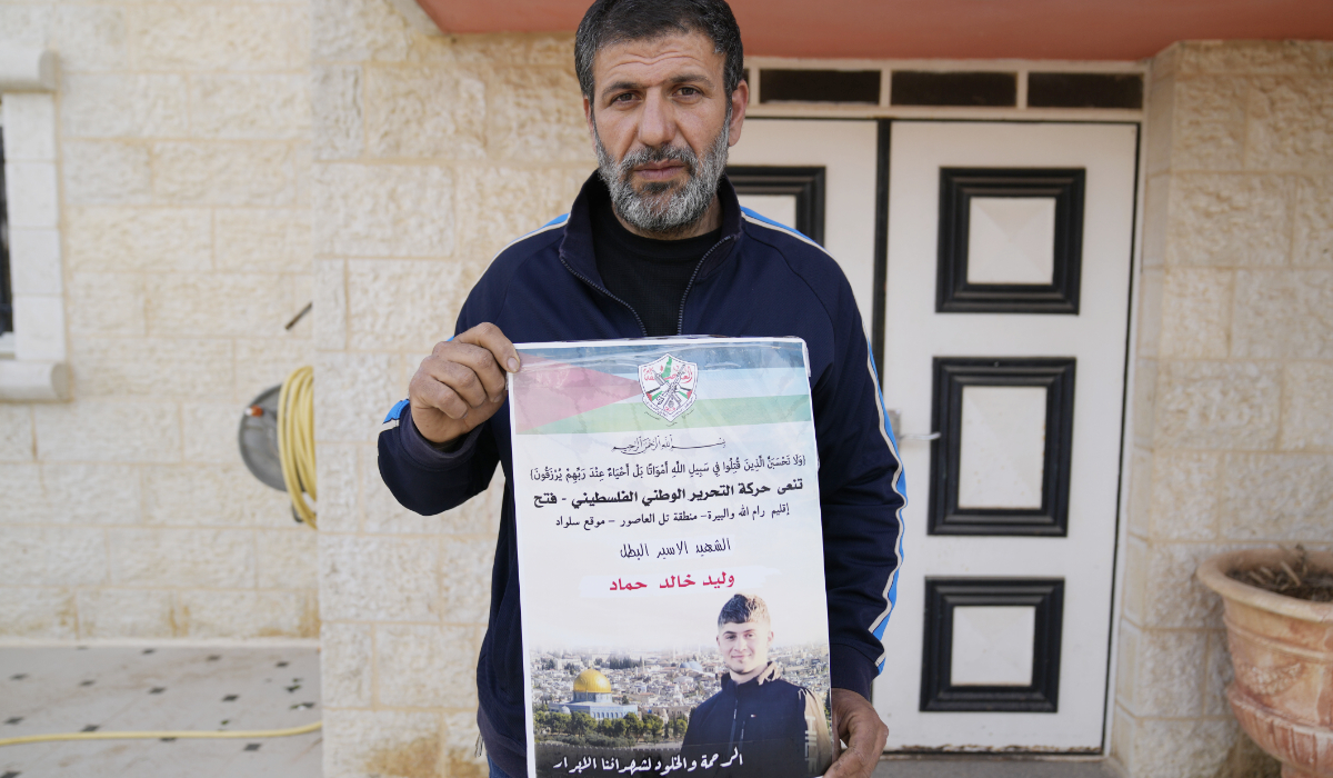 Khalid Ahmad holds a poster of his 17-year-old son, Waleed, who died in an Israeli prison. (AP)