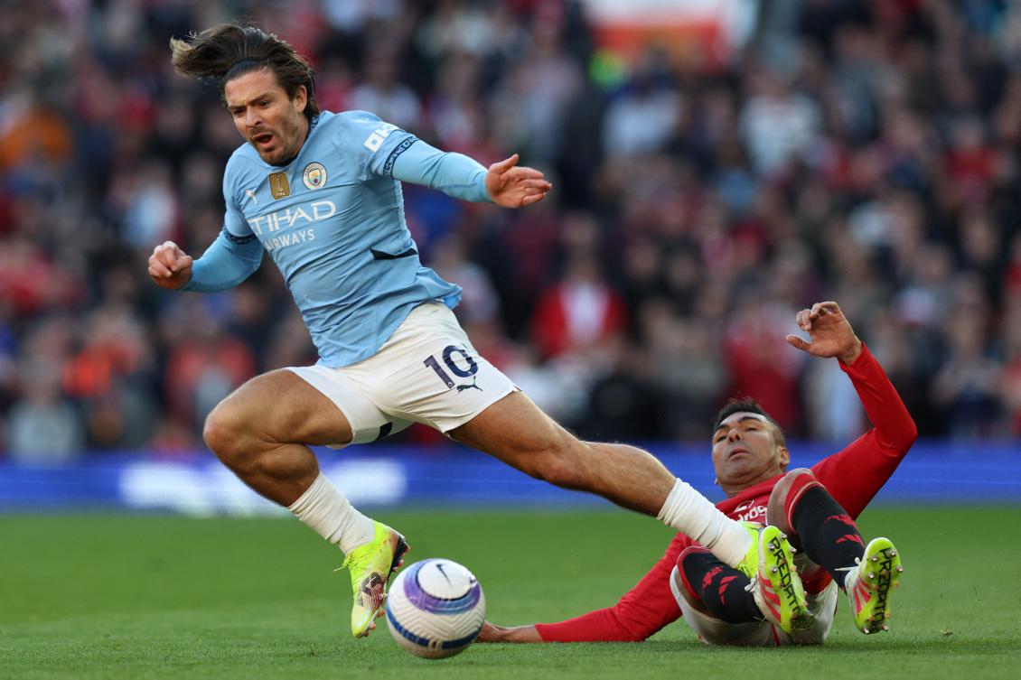 Manchester United’s Brazilian midfielder #18 Casemiro (R) tackles Manchester City’s English striker #10 Jack Grealish (L) during the English Premier League football match between Manchester United and Manchester City at Old Trafford. (AFP)