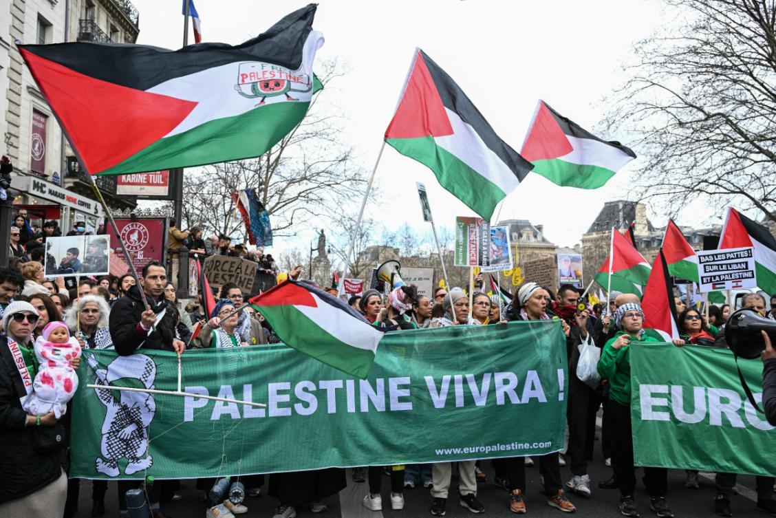 Protestors wave Palestinian flags and hold a banner reading "Palestine will live" during a demonstration on Place de la Republique in Paris on March 22, 2025, as part of the international day against racism and fascism. (File/AFP)
