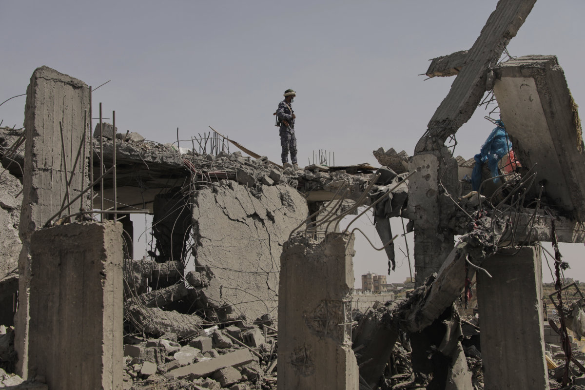 A Houthi security officer stands over the debris of a destroyed building reportedly hit by US airstrikes in Sanaa, Yemen, on April 7, 2025. (AP Photo)