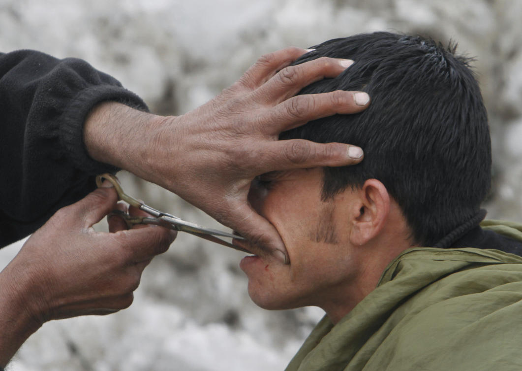 An Afghan street barber man, left, trims the mustache of a customer in Kabul on Feb. 9, 2012. (AP file photo)