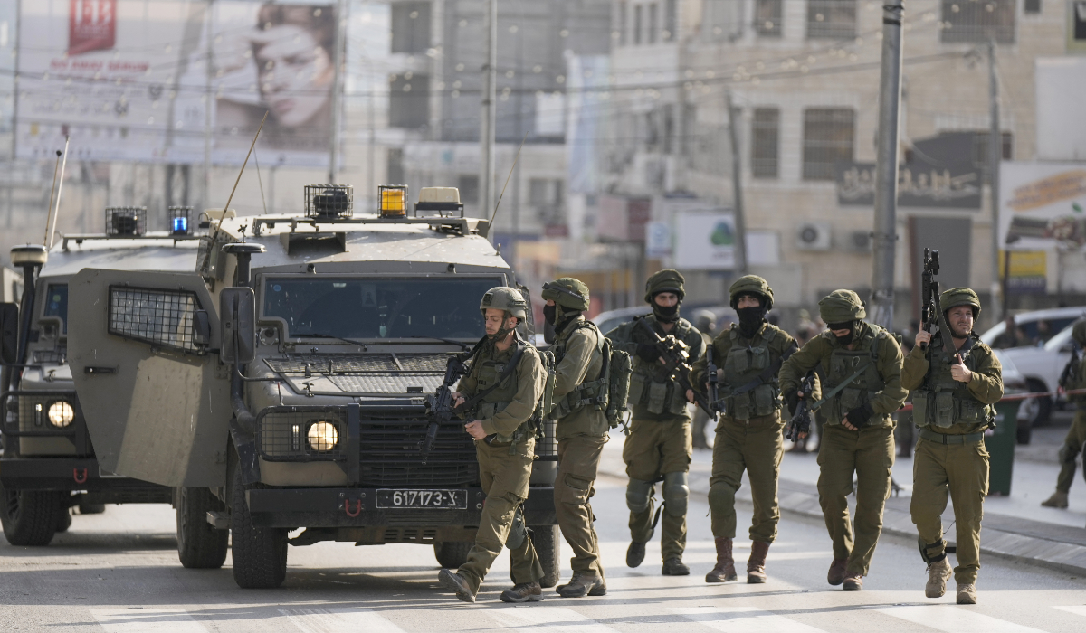 Israeli soldiers take up positions at the scene of a Palestinian shooting attack on an Israeli car at the Hawara checkpoint, near the West Bank city of Nablus, Sunday, Feb. 26, 2023. (AP)