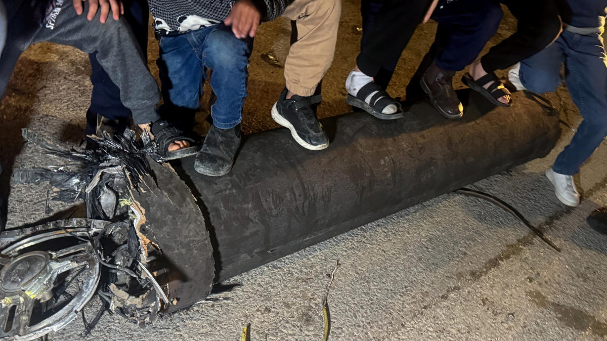 Palestinian children hold their feet on a missile fragment after a Houthi missile launch toward Israel, near Hebron in the Israeli-occupied West Bank on April 13, 2025. (Reuters)