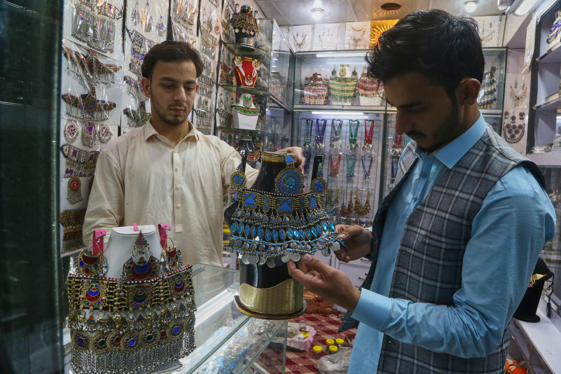 An Afghan national, left, attends to a customer at his Afghan traditional jewellery shop at a market in Peshawar, Pakistan, Tuesday, April 8, 2025. (AP)