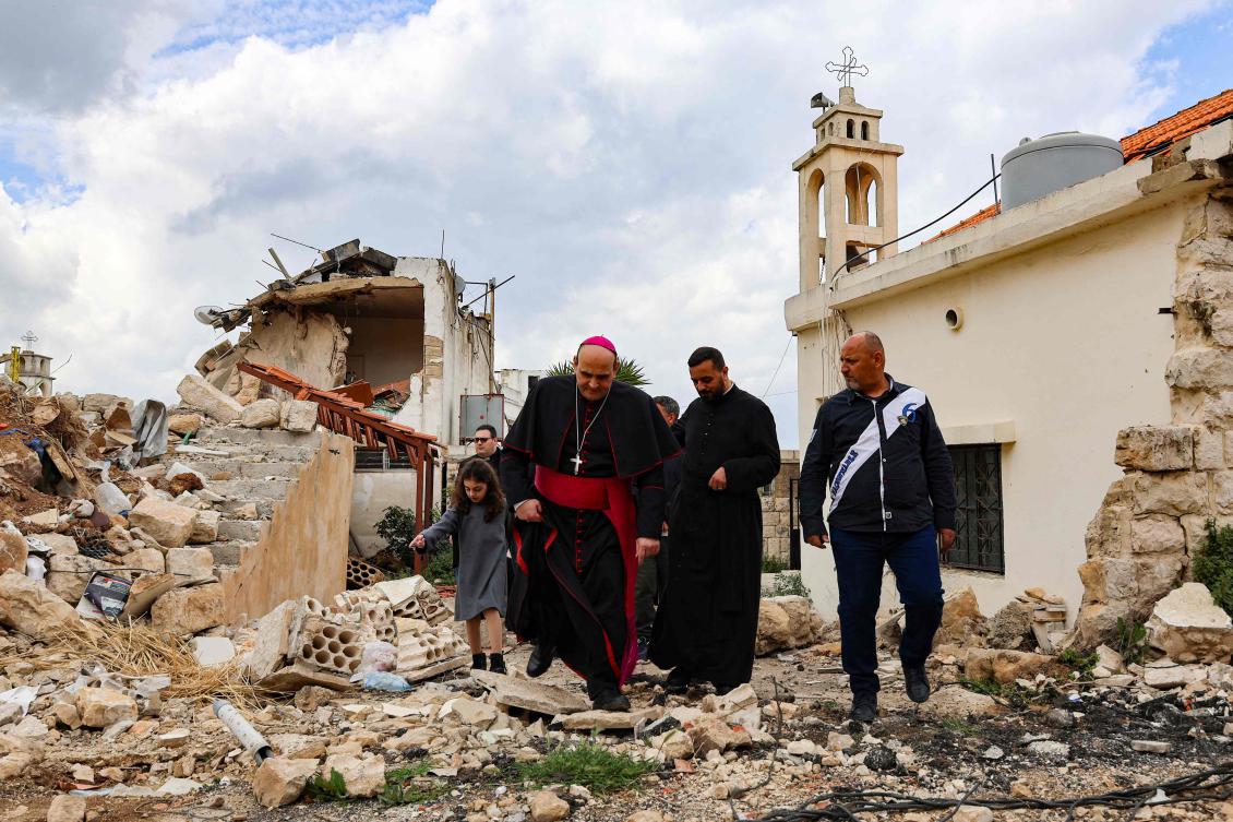Papal envoy, Italian prelate of the Catholic Church Paolo Borgia walks with a Lebanese priest in front of a building destroyed by Israeli bombing in the recent war, during his visit to the southern Lebanese town of Khiam on Palm Sunday on April 13, 2025. (AFP)