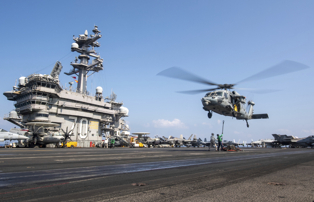 a military helicopter hovers over the uss carl Vinson aircraft carrier. (AP)