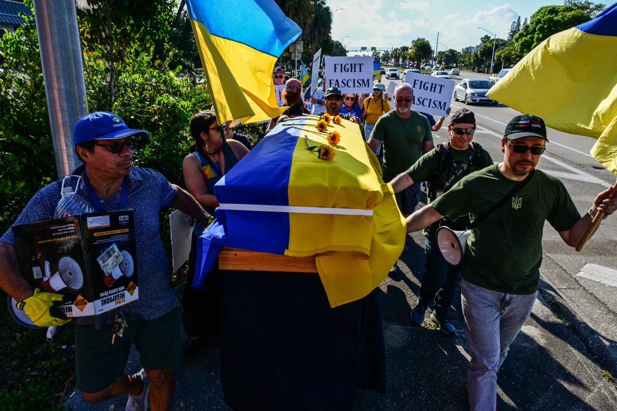 Activists carry a makeshift coffin draped with the Ukraine flag as they march in the "Ukraine will never surrender" protest near US President Donald Trump's Mar-a-Lago resort in West Palm Beach, Florida, on March 14, 2025 (AFP)