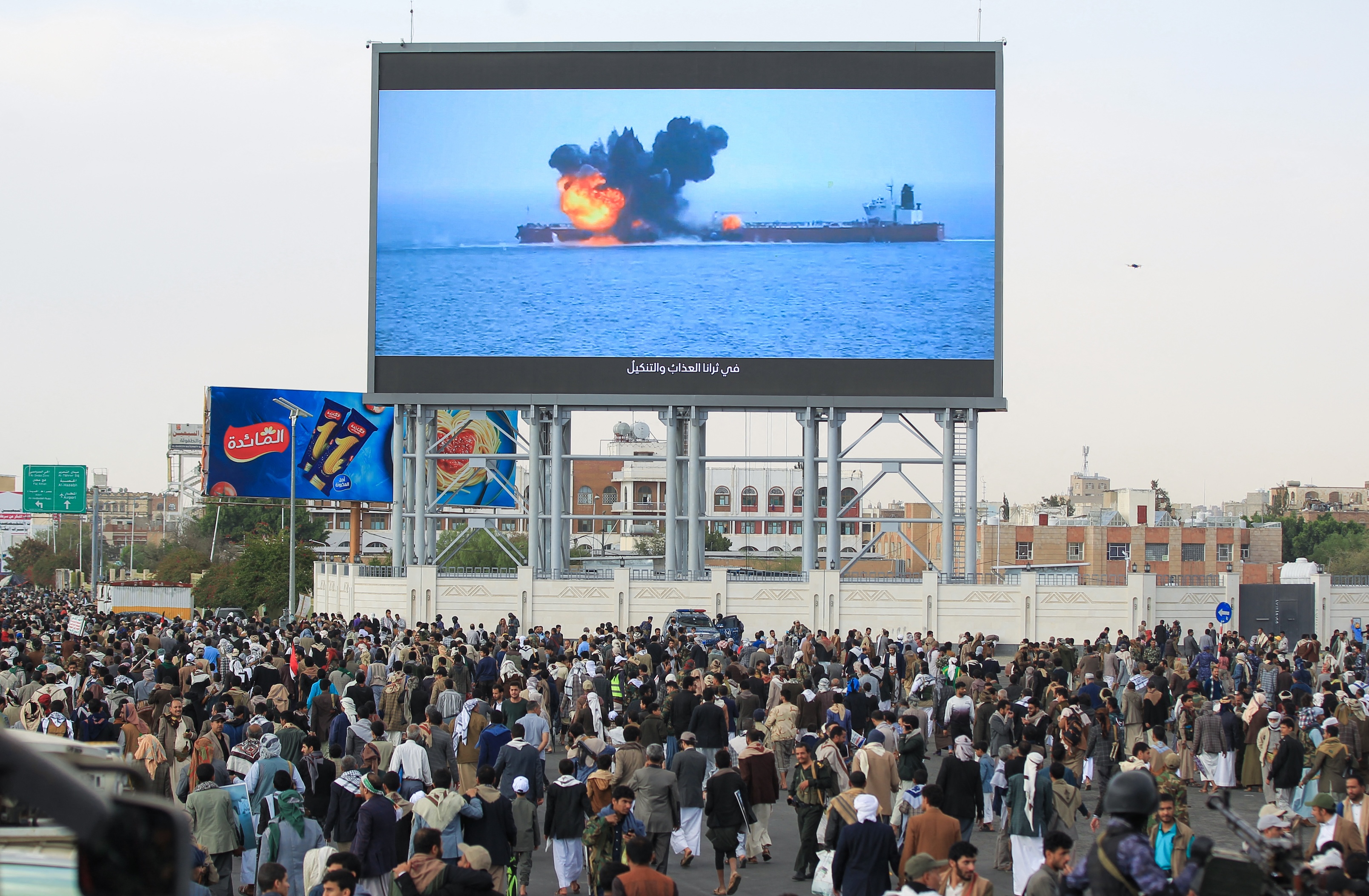 Images of a fireball exploding on a cargo ship are shown on a giant screen during a protest called for by Yemen's Houthi movement in Sanaa, Mar. 17, 2025. (AFP)