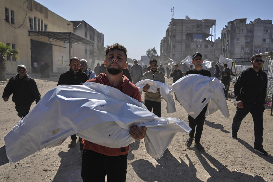 Mourners carry white sacks covering the bodies of members of the Abu Al-Rous family, killed when an Israeli airstrike struck their displacement tent overnight, during their funeral in Khan Younis, southern Gaza Strip. (AP)