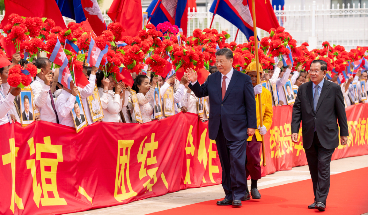 Chinese President Xi Jinping waves to the crowd as Cambodian Senate President Hun Sen stands beside him during a farewell ceremony at Phnom Penh International Airport on Friday. (AP)