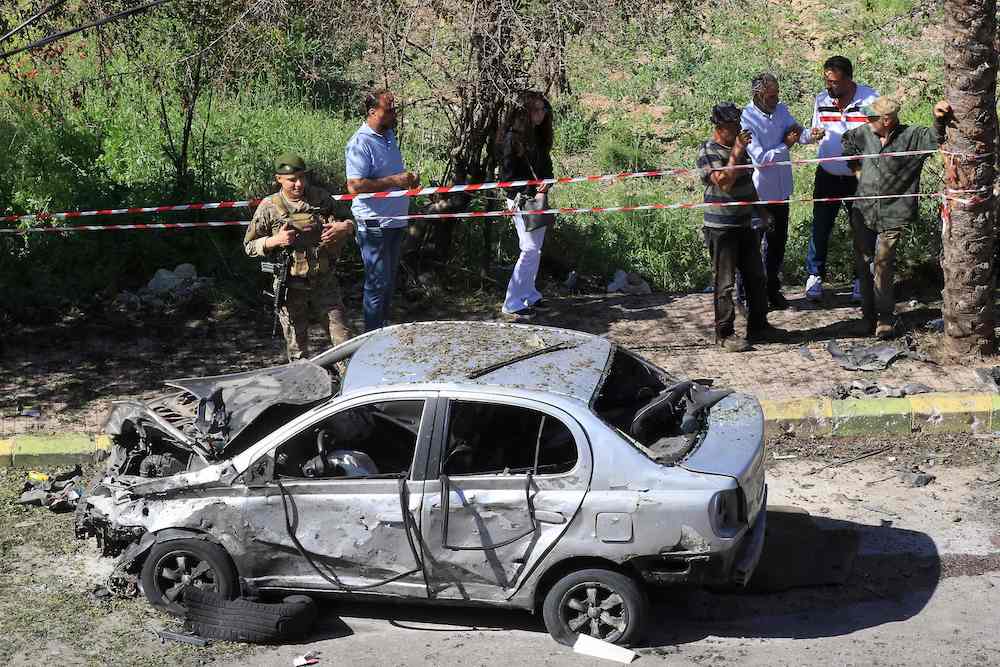 A Lebanese army soldier stands next to a burnt-out vehicle at the site of an explosion in Braiqaa in south Lebanon's Nabatiyeh district, on April 20, 2025. (AFP)