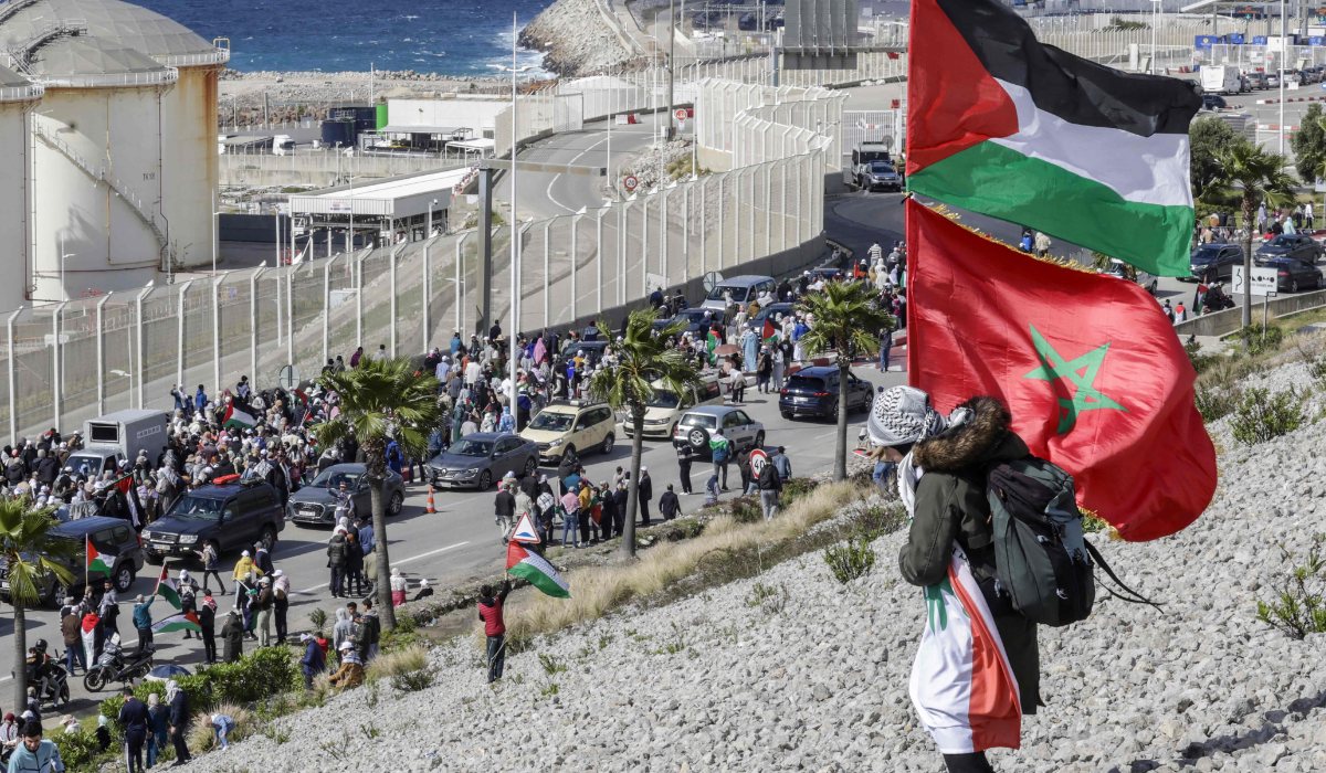 A woman holds Palestinian, Moroccan and Lebanese flags as protesters march towards the port of Tanger-Med against the planned docking of a ship said to be carrying fighter jet parts to Israel in Tangiers on April 20, 2025. (AFP)