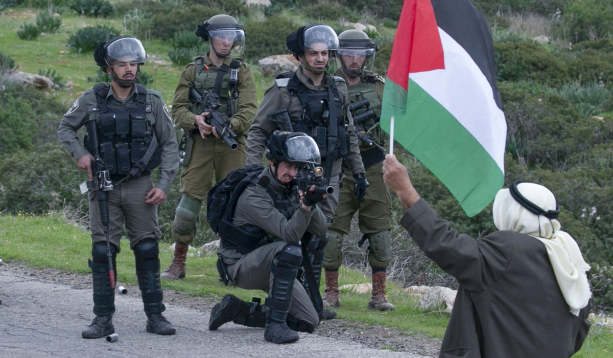 A man brandishes a Palestinian flag as members of the Israeli border police clash with Palestinians protesting Israeli settlements and a controversial US-brokered peace plan, in the Jordan Valley area of the occupied West Bank, on February 25, 2020. (AFP file photo)