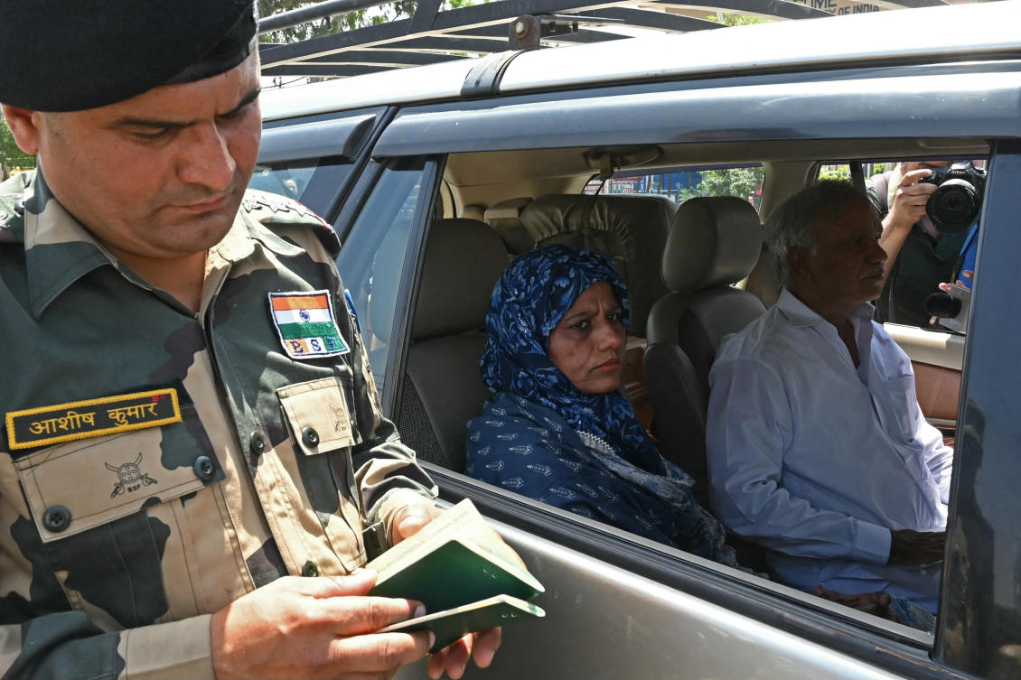An Indian Border Security Force (BSF) personnel (L) checks passports of Pakistan citizens returning to their country through the India-Pakistan Wagah border post. (AFP)