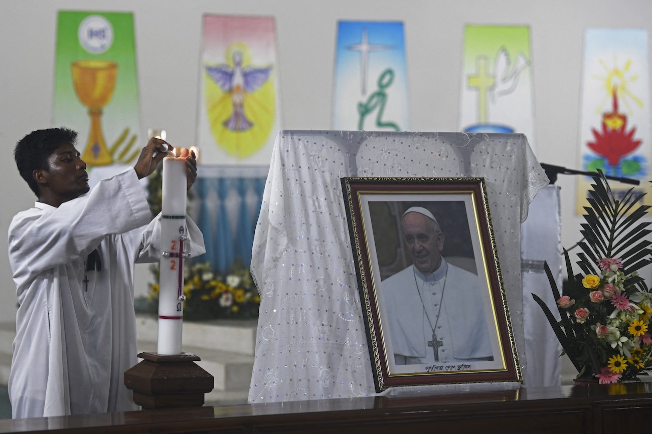 A church attendant lights a candle beside a portrait of late Pope Francis before the start of a special service at St. Mary’s Cathedral in Dhaka on April 22, 2025. (AFP)