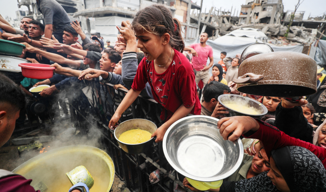 Palestinians wait to receive food cooked by a charity kitchen in Beit Lahia, northern Gaza Strip. (Reuters)