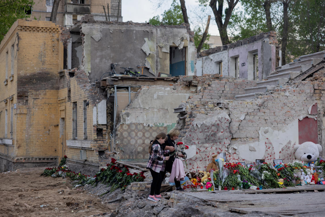 Local residents lay flowers at the site of a destroyed residential building following a Russian missile attack in Kyiv. (AFP)